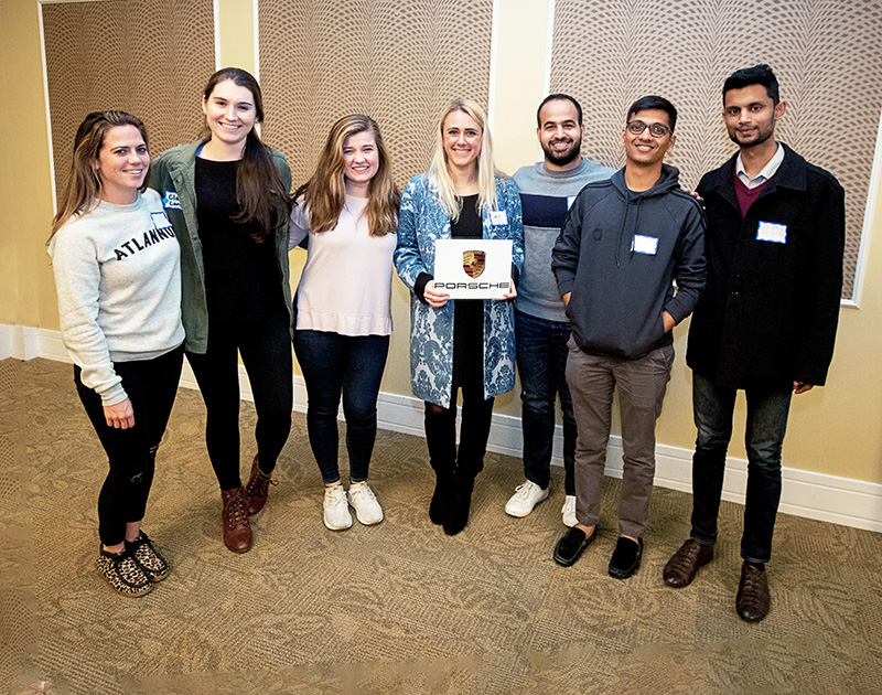 Goizueta Gold first-place winners are, from left, Alexa Newfield, Claire Long (mentor), Jordyn Hodge, Emma Sveen, Mustapha Sakr, Naveen Srikakulam, and Steven Saldanha. Photo taken last fall during Team Reveal, where students learned of project assignments.