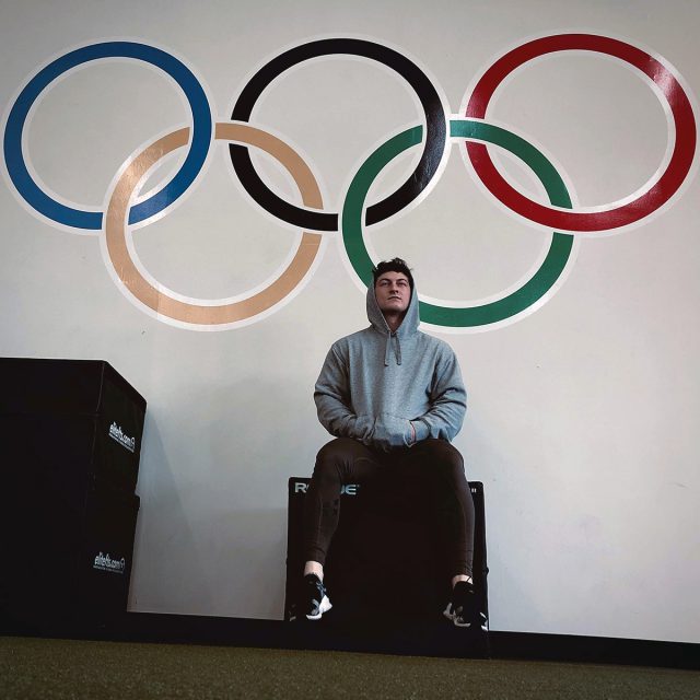 Matthew Jones sits in front of olympic rings