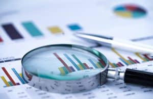 Magnifying glass on charts graphs spreadsheet paper. Financial development, Banking Account, Statistics, Investment Analytic research data economy, Stock exchange trading, Business office company meeting concept.