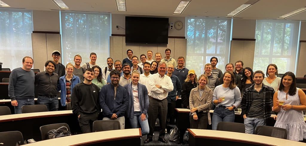 Ray Hill posing with students after teaching his final class at Goizueta Business School