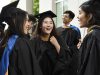 Three recently graduated Goizueta Alumni pose in cap and gowns after commencement