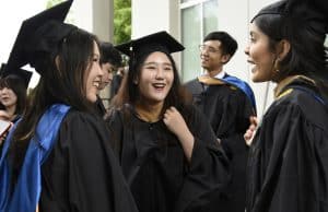 Three recently graduated Goizueta Alumni pose in cap and gowns after commencement