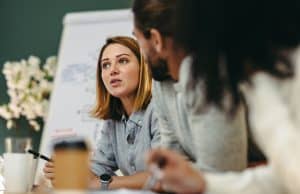 Getty Images - from US News & World Report. Woman in the middle of speaking while sitting at table with other people.