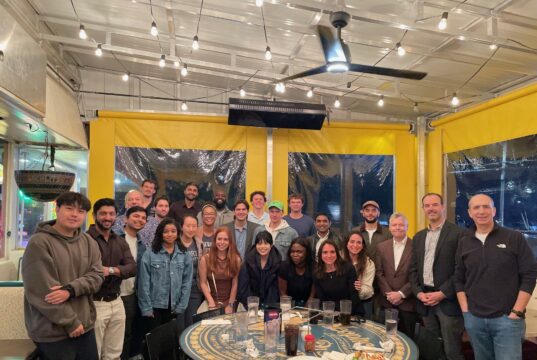 Leadership Development Fellows with faculty and executive coaches at a pizza gathering.