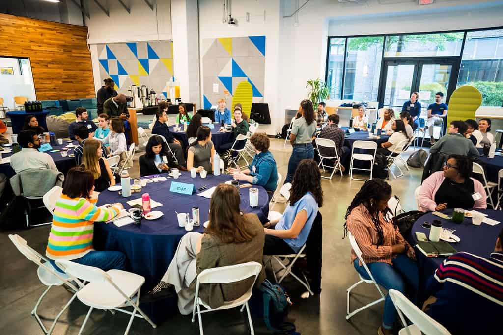 Students seated at tables collaborate during the Climate Design Challenge at The Hatchery.