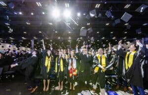 Goizueta Business School graduates celebrate by tossing their caps in the air during the Class of 2026 commencement ceremony at Gas South Arena.