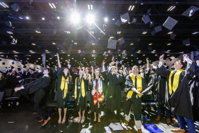 Goizueta Business School graduates celebrate by tossing their caps in the air during the Class of 2026 commencement ceremony at Gas South Arena.