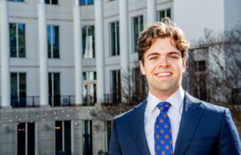 A headshot of Goizueta BBA Grant Huddleston standing outside of the business school building