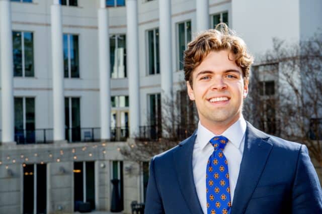 A headshot of Goizueta BBA Grant Huddleston standing outside of the business school building
