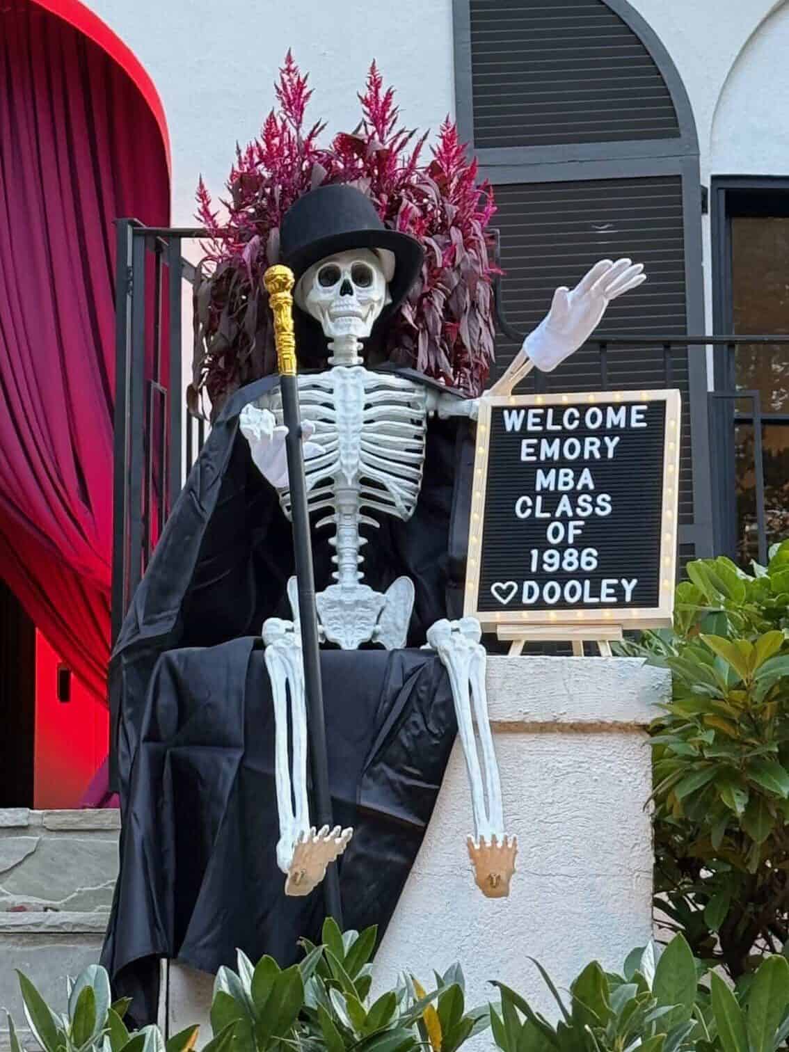 Dooley, Emory University’s skeleton mascot, wears a black top hat and cape and holds a gold-topped cane beside a sign welcoming the MBA Class of 1986.