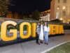 Goizueta Celebrates 2026 Homecoming and Reunion Weekend Three women pose in front of large gold GOIZUETA letters at an outdoor evening celebration on Emory’s campus.