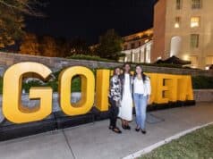 Goizueta Celebrates 2026 Homecoming and Reunion Weekend Three women pose in front of large gold GOIZUETA letters at an outdoor evening celebration on Emory’s campus.